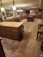 Kitchen featuring wooden walls, a breakfast bar area, pool table, wainscoting, and tile counters