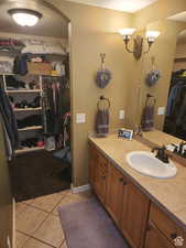 Bathroom with a walk in closet, vanity, and tile patterned flooring