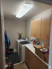 Washroom featuring washer and dryer, cabinet space, a textured ceiling, and tile patterned flooring