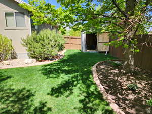 View of yard with an outdoor structure, a fenced backyard, and a shed