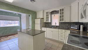Kitchen with a sink, light tile patterned floors, white appliances, visible vents, and a toaster