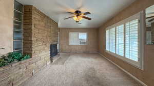 Unfurnished living room featuring a textured ceiling, a healthy amount of sunlight, a fireplace, and ceiling fan