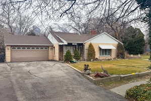 View of front of house with driveway, a front lawn, a garage, a shingled roof, and a chimney