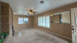 Spare room featuring carpet flooring, a ceiling fan, a textured ceiling, baseboards, and visible vents
