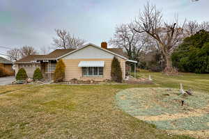 View of front facade featuring a chimney, a garage, and a front yard