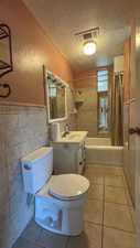 Bathroom featuring tile patterned floors, visible vents, toilet, and a textured ceiling