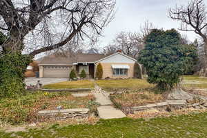 Ranch-style house with a front lawn, a chimney, a garage, and concrete driveway