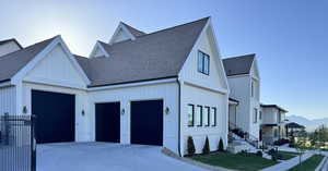 View of front of property with board and batten siding, a shingled roof, and driveway