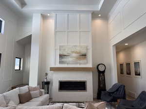 Living room with recessed lighting, a towering ceiling, a glass covered gas fireplace with blower