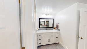 Bathroom with wood tiled floor, vanity, and a textured ceiling