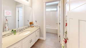 Bathroom with baseboards, shower / washtub combination, and vanity