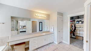 Bathroom featuring a textured ceiling, vanity, a spacious closet, a stall shower, and tile patterned flooring