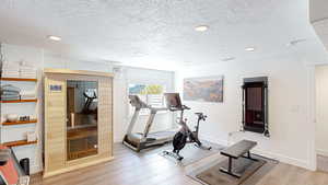 Workout area with baseboards, a textured ceiling, wood finished floors, and recessed lighting