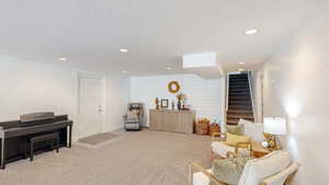 Sitting room with carpet floors, a textured ceiling, stairs, and recessed lighting
