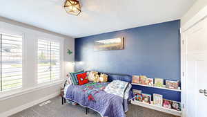 Carpeted bedroom featuring baseboards, a textured ceiling, and visible vents
