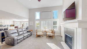 Living area featuring baseboards, a fireplace, a high ceiling, and light colored carpet