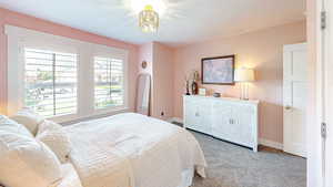 Bedroom featuring baseboards, an inviting chandelier, and carpet