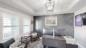 Home office with baseboards, a notable chandelier, an accent wall, and a raised ceiling