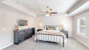 Bedroom with baseboards, ceiling fan, carpet flooring, and a raised ceiling