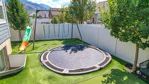 View of yard with a fenced backyard, a playground, a mountain view, and a trampoline