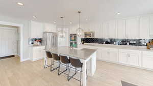 Kitchen with white cabinetry, stainless steel appliances, an inviting chandelier, and light wood-type flooring