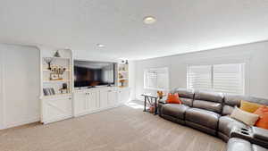 Living area featuring baseboards, a textured ceiling, and light carpet