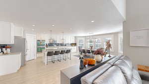 Living area featuring light wood-style flooring, recessed lighting, and a textured ceiling