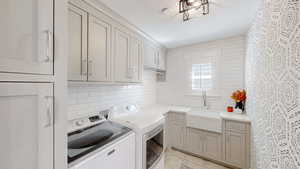Laundry room featuring washer and clothes dryer, light tile patterned floors, a textured ceiling, a sink, and cabinet space