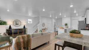 Living room with recessed lighting, light wood-style flooring, and stairway