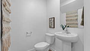 Half bath with baseboards and toilet