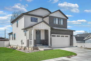 View of front of house featuring board and batten siding, concrete driveway, fence, and an attached garage