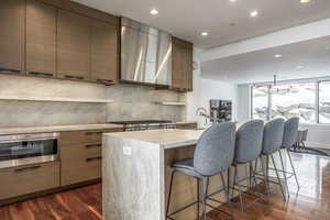 Kitchen with modern cabinets, wall chimney exhaust hood, decorative backsplash, a sink, and recessed lighting