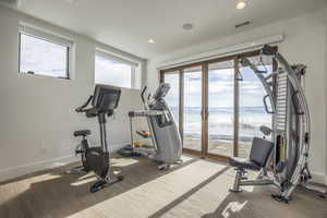 Exercise room featuring baseboards, recessed lighting, and a water view