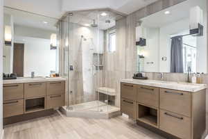 Bathroom with a stall shower, two vanities, decorative backsplash, and recessed lighting