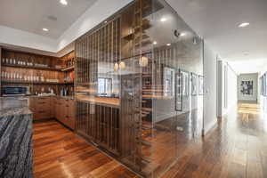 Bar area featuring black microwave, wood finished floors, and recessed lighting