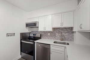 Remodeled kitchen with quartz countertops, white cabinets, and new appliances with stainless steel finishes