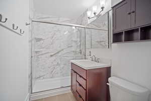 Bath featuring toilet, vanity, and a large shower