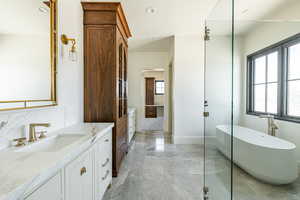 Bathroom featuring a sink, two vanities, a soaking tub, marble finish floor, and recessed lighting
