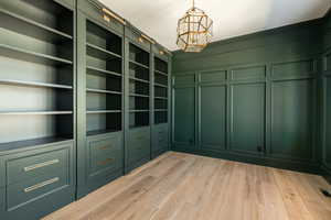 Walk in closet with a notable chandelier and light wood finished floors