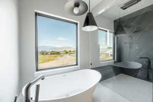 Full bath with a freestanding bath, a mountain view, and a tile shower