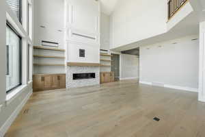 Unfurnished living room featuring plenty of natural light, visible vents, and light wood-style floors