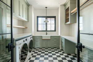 Clothes washing area featuring tile patterned floors, a sink, cabinet space, and washing machine and dryer