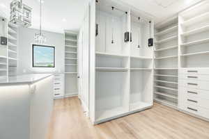 Spacious closet featuring a notable chandelier and light wood-style flooring