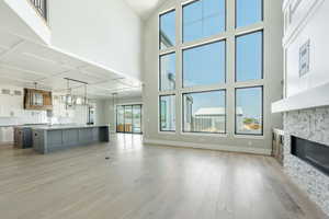 Unfurnished living room featuring a high ceiling, light wood finished floors, baseboards, and a fireplace