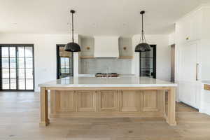 Kitchen featuring backsplash, light wood finished floors, custom exhaust hood, and recessed lighting