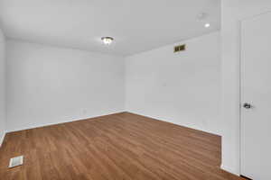 Unfurnished room featuring wood finished floors, baseboards, and visible vents