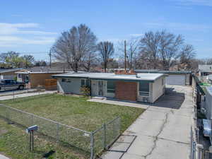 Mid-century home featuring an outbuilding, a detached garage, a front yard, and fence private yard