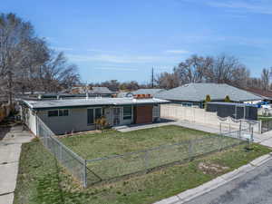 View of front of home featuring concrete driveway, a fenced front yard, and a front lawn