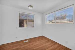 Empty room featuring baseboards, visible vents, and wood finished floors