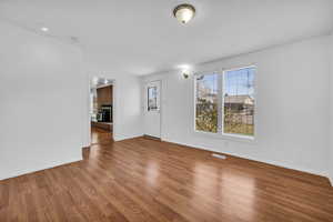 Interior space with baseboards, a fireplace, visible vents, and wood finished floors